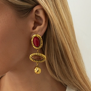 Close-up of vintage resin drop earrings with gold hammered metal and red gemstones