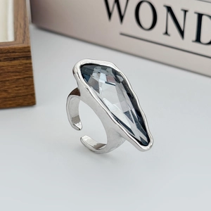 Dettaglio di un anello color argento con un grande cristallo acrilico grigio sfaccettato