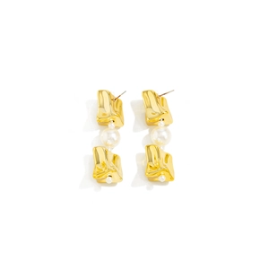 Détail des boucles d'oreilles dorées irrégulières avec grandes perles blanches