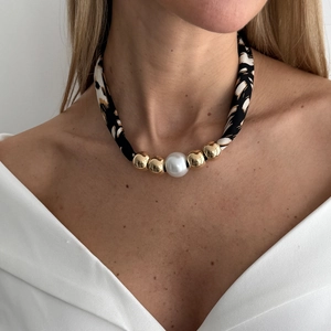Detail van luipaardstof ketting met grote parel en gouden glanzende metalen kralen