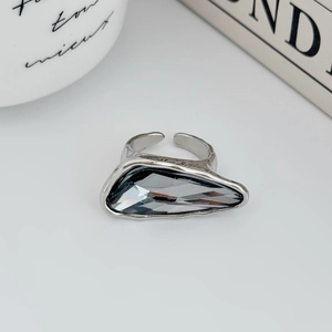 Macro anello argento con gemma grigia geometrica su sfondo minimalista