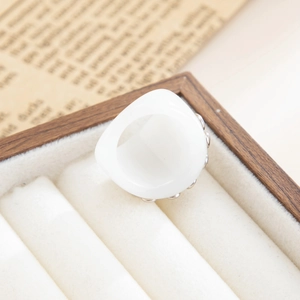 Close-up of white resin ring with silver metal studs displayed in a wooden jewelry box