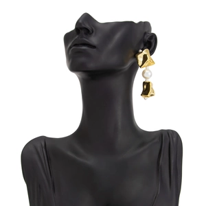 Gros plan de boucles d'oreilles dorées carrées irrégulières avec perle blanche