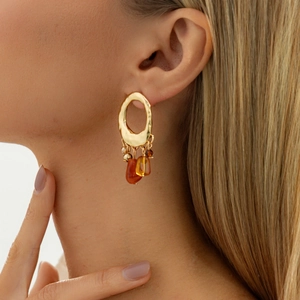 Macro detail of Bohemian style gold earrings with amber resin and floral drop design