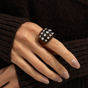 Detail of dark brown resin ring with inlaid sparkling rhinestones in punk style