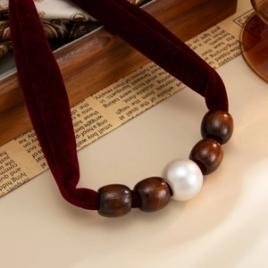 Macro-opname van retro fluwelen ketting met houten kralen en faux parel op oud papier