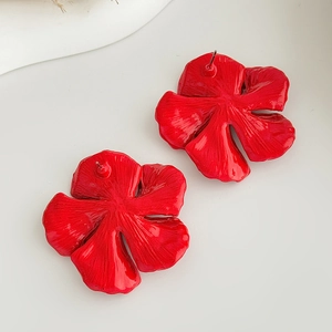 Macro detail of red floral stud earrings showing textured enamel petals and glossy finish