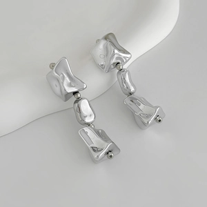 Détail macro de boucles d'oreilles argentées style lave avec finition métallique polie