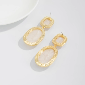 Close-up of vintage geometric resin earrings with marble pattern and textured gold frame