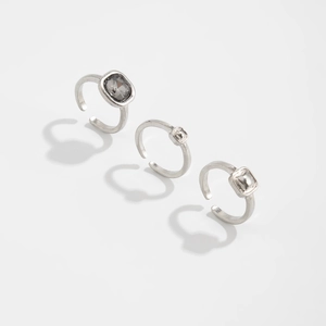 Dettaglio del set di tre anelli in argento con cristalli grigi quadrati e design aperto