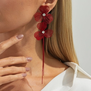 Close-up of long red floral tassel earrings with intricate woven petals and crystals