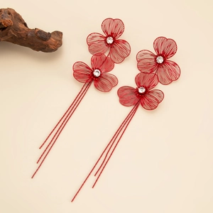 Detailed close-up of red filigree flower earrings with long tassels and crystal center