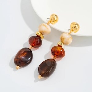 Detail of vintage beaded earrings with amber resin and gold metal beads on ceramic