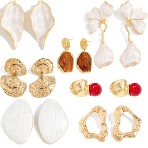 Set mit goldenen Ohrringen, weißen Emaille-Blüten, Bernstein-Harz und geometrischen Blättern