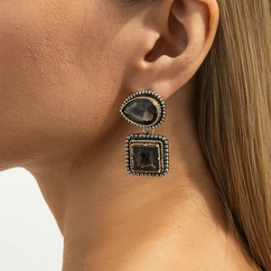 Gros plan de boucles d'oreilles vintage avec pierres brunes et bordures dorées et argent