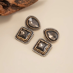 Détail de boucles d'oreilles vintage avec pierres grises et textures métal or-argent