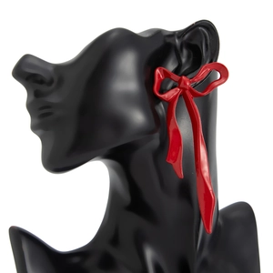 Vintage red metal bow earrings with long ribbon design on a black silhouette model