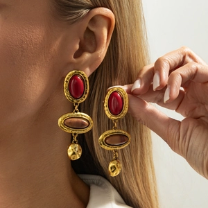 Nahaufnahme vintage goldener Tropfenohrringe mit roten und braunen ovalen Harzsteinen