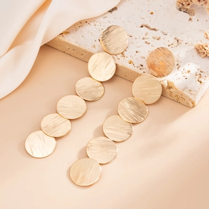 Golden long drop earrings with six brushed metal discs on elegant silk and stone background