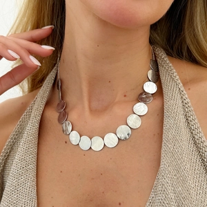 Close-up of minimalist silver disk necklace with brushed metal finish on female model