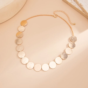 Detailed macro view of gold circular metal discs with brushed texture on fashion necklace