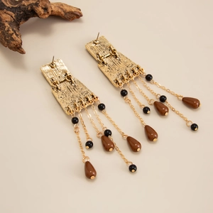 Détail de boucles d'oreilles vintage dorées avec perles noires et gouttes marron