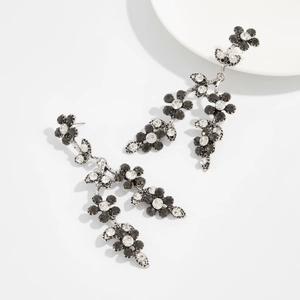 Détail de boucles d'oreilles pendantes argentées avec éventail et strass noirs chic