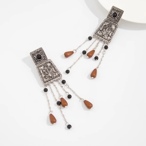 Vue détaillée des boucles d'oreilles argentées vintage avec gravures et pompons
