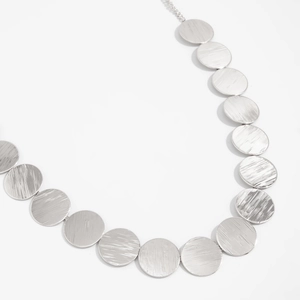 Detailed view of silver disc necklace with brushed metal texture and geometric link design