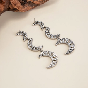 Détail de longues boucles d'oreilles bohèmes avec triple lune et finition argent vintage