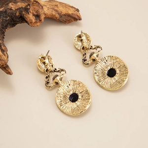 Vue détaillée de boucles d'oreilles pendantes vintage dorées avec gravures et centres noirs