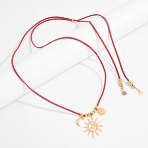 Dettaglio della collana in corda rossa con ciondoli a sole e luna dorati stile boho