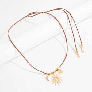 Dettaglio di pendenti a luna e sole bohémien su collana in cordoncino di velluto marrone