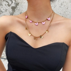 Detail of double-layer necklace featuring pink resin and golden metal butterfly charms
