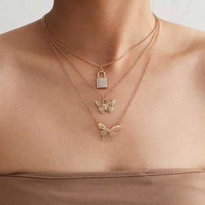 Detailed close-up of triple-layered gold necklaces with lock and butterfly pendants