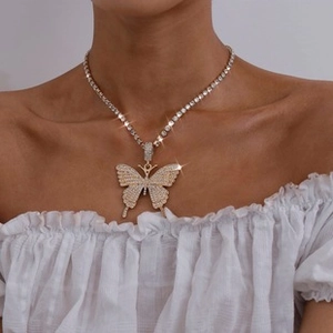 Close-up of sparkling butterfly pendant on a silver-tone tennis chain worn by a model
