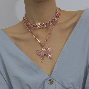 Close-up of pink crystal butterfly pendant necklace set worn with light blue top