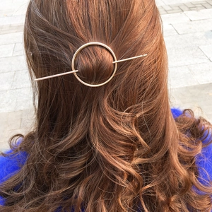 Minimalistische geometrische runde Haarnadel in Goldoptik auf langem braunem Haar