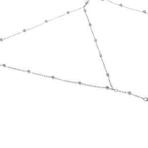 Dettaglio catena corpo argento con perline lucide e maglie sottili in stile minimalista