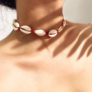 Detail of handmade seashell choker with gold accent and red woven cord on model skin