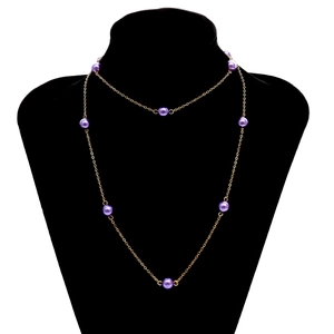 Elegante collar de cadena dorada con cuentas púrpuras sobre un maniquí de cuello negro