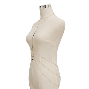 Détail d'une chaîne de corps multicouche dorée avec perles noires sur un mannequin