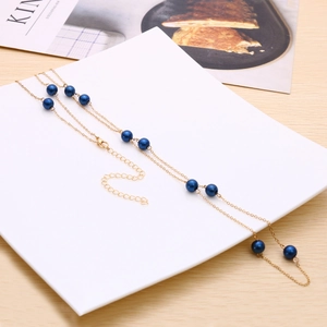 Detalle del collar dorado con cuentas azules y cierre de mosquetón ajustable fino