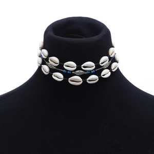 Detailed close-up of bohemian layered shell necklace with turquoise beads on black stand