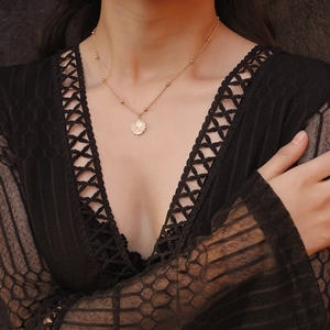 Dettaglio di una collana dorata con pendente VIP in rilievo su sfondo di pizzo nero