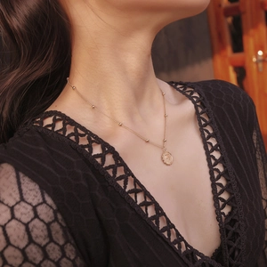 Primo piano di un ciondolo segno Vergine dorato su una collana a perline indossata da modella