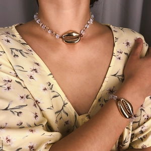 Dettaglio di set collana e bracciale bohémien con conchiglie dorate e perline di opale