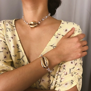 Dettaglio della collana con conchiglia dorata bohémien e bracciale di perle opache