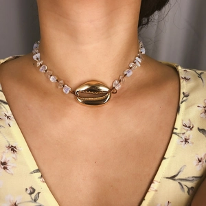 Dettaglio della collana bohémien con conchiglia e pietre bianche su abito estivo