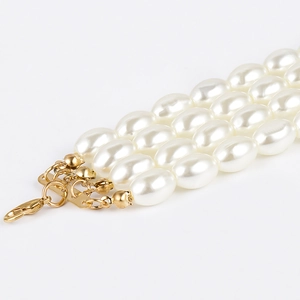 Detailed close-up of triple-strand cream pearl necklace with gold lobster clasp